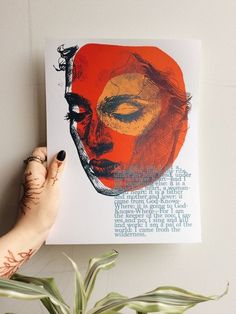 a woman's hand holding up a poster with an image of a face on it