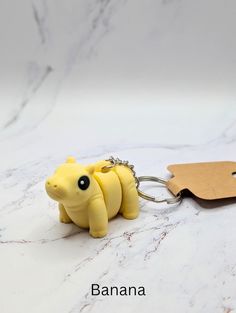 a banana shaped keychain is sitting on a marble surface with a wooden tag attached to it