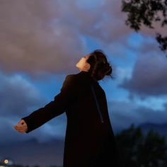 a woman is flying a kite in the sky at night with her arms spread wide