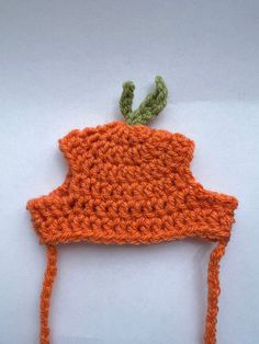 an orange crocheted hat with a green leaf sticking out of it's brim