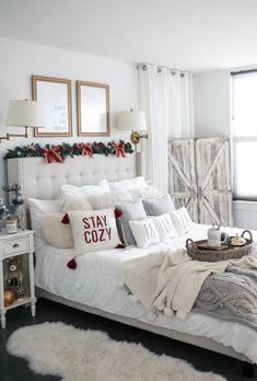 a bedroom with white bedding and christmas decorations on the headboard, windows, and rugs