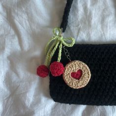 a crocheted bag with a heart on the front and two cherries attached to it