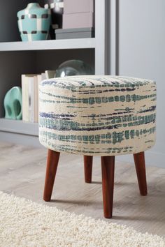 a small stool sitting on top of a wooden floor next to a book shelf filled with books