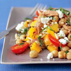 a white plate topped with chickpeas, peppers and cheese next to a fork