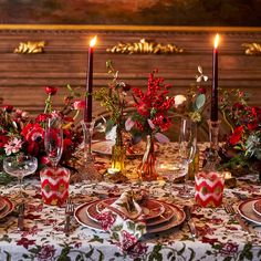 the table is set with red flowers and candles