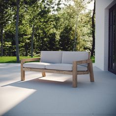 a white couch sitting on top of a patio next to a tree filled forest in the background