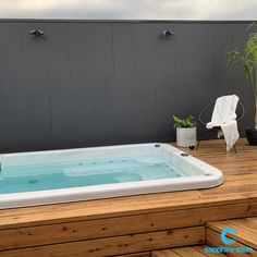 a hot tub sitting on top of a wooden deck next to a potted plant