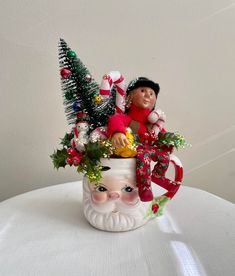 a christmas planter with a santa clause head and candy canes in it on a white table