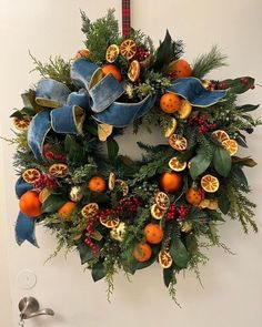 a christmas wreath with oranges and greenery hanging on the wall next to a door