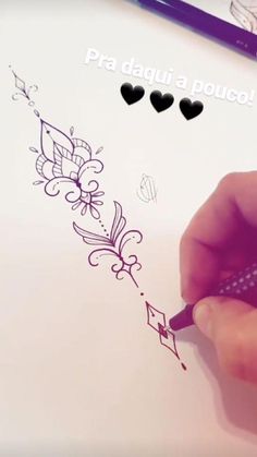 a person is writing on a piece of paper with hearts and flowers drawn on it