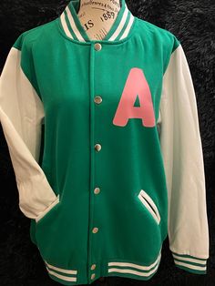 A - Ivy League... Lightweight, unisex varsity jacket. Pink vinyl lettering. Green jacket, white arms and accents. Dry on low or no heat. Do not iron on print. Varsity Jacket Pink, Virginia State University, Hampton University, Pink Vinyl, Alpha Kappa Alpha, Ivy League, Striped Sleeve, No Heat, Vinyl Lettering