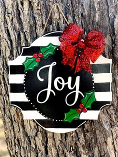 a christmas ornament hanging on a tree with the word joy painted on it