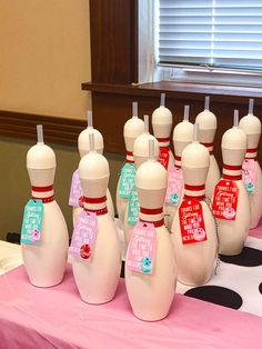 a group of white bowling pins sitting on top of a pink tablecloth covered table