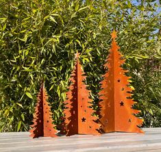 three metal christmas trees sitting on top of a wooden table