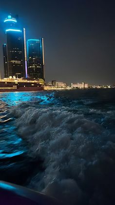 the city lights shine brightly in the night sky as boat speeds through the water on its way to shore