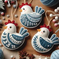 three handmade christmas ornaments on a wooden table with balls of yarn and twine