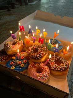 a box filled with donuts covered in frosting and lit candles