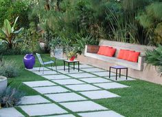 a garden with grass, plants and benches in the middle of it is surrounded by greenery