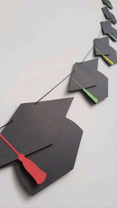 a long line of black and red graduation caps hanging on a string that is attached to a white wall