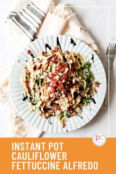 a white plate topped with pasta covered in sauce and seasoning next to a fork