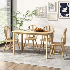 a dining room table and chairs with pictures on the wall above it, along with a rug