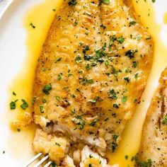 two pieces of fish on a plate with lemon sauce and garnished with parsley