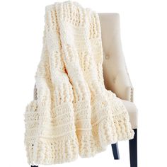 a chair with a blanket on top of it and a white chair next to it