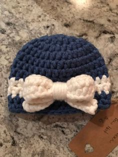 a crocheted hat with a white bow on it sitting on top of a counter