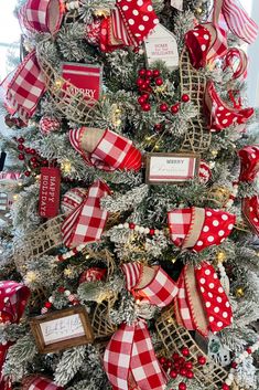 a christmas tree decorated with red and white ribbons, bows and tags on the top