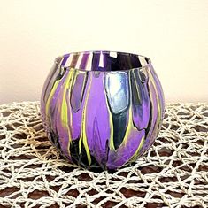 a purple glass vase sitting on top of a white tablecloth covered table with crocheted doily