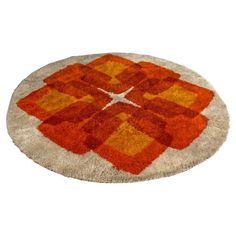 an orange and yellow area rug on a white background with the center design made out of squares