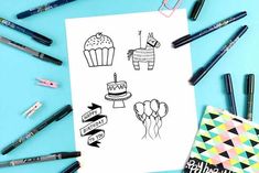 some markers and pens are laying on a sheet of paper with an image of cupcakes