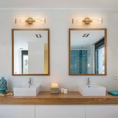 two bathroom sinks with mirrors above them and candles on the counter in front of them