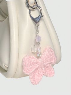 a white purse with a pink crochet bow on the front and a silver chain attached to it