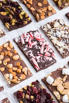 many different types of chocolates and nuts are arranged on a white surface with candy canes