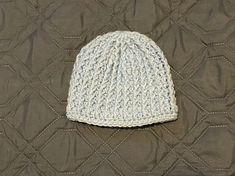 a white knitted hat sitting on top of a quilt