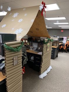 an office cubicle decorated for christmas with snowflakes on the roof and decorations