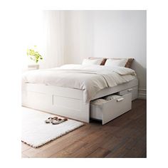 a bed with two drawers underneath it and a rug on the floor next to it