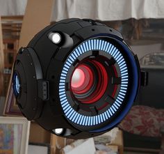 a black and blue light up object with red lights on it's side in a room