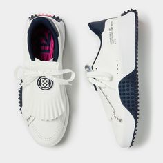 a pair of white shoes with blue and pink details on the soles, one is being