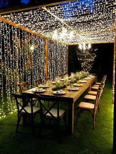 an outdoor dining area with lights strung from the ceiling and table set up for dinner