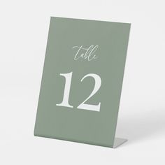 a table number card with the numbers twelve and twelve in white on a green background