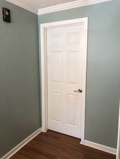 an empty room with a white door and hard wood floor