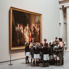 a group of children standing in front of a painting on display at a museum with their arms around each other