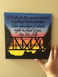 a person holding up a painting with a quote on it that reads, live life for the moment because everything else is unentifia