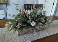 a wooden box filled with lots of greenery and pine cones on top of a table