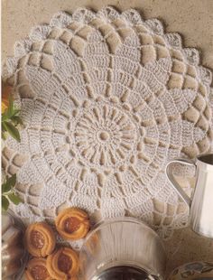 a crocheted doily with coffee and pastries on the table next to it