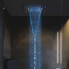 a shower head with blue water running from it's sides in a bathroom setting