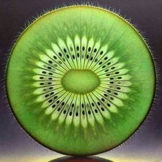 a kiwi cut in half sitting on top of a reflective surface with its reflection