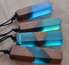 three pieces of wood with blue and green glass in them sitting on a table next to black beads